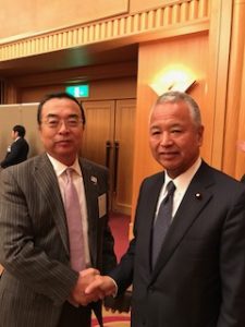 握手する秋山本部長と甘利衆議院議員